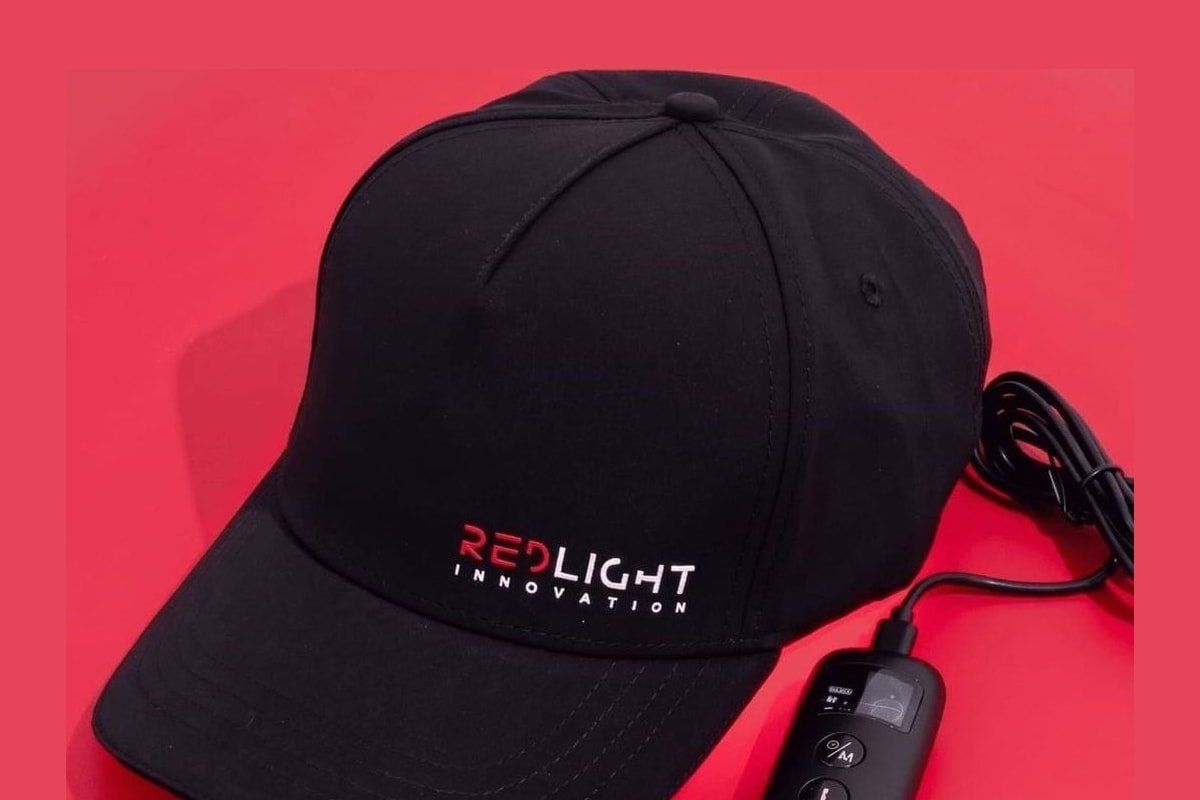 RedLight Innovation Hat Pro on a red background, with the red LED panel visible inside the cap.