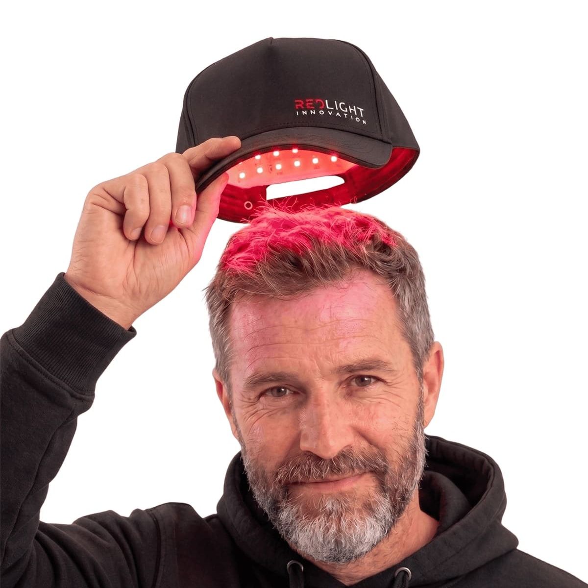 A man wearing the RedLight Innovation Hat Pro with the red LEDs switched on.